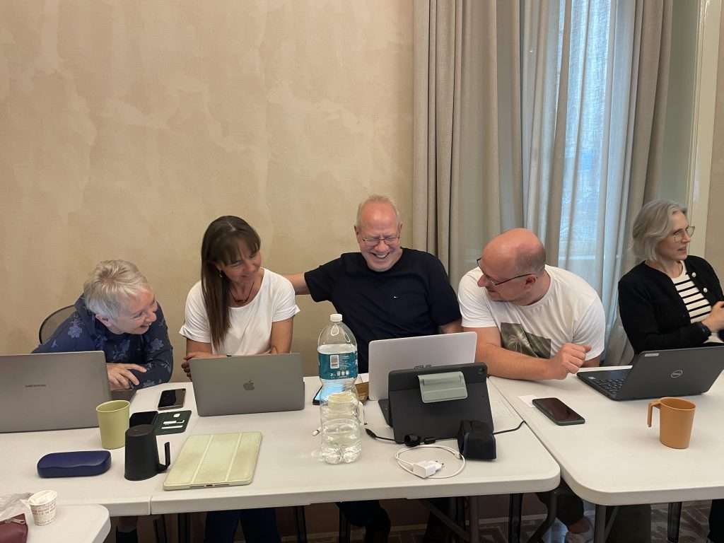 Enseignants riant ensemble en testant des outils numériques sur ordinateurs portables lors d’une formation ELA